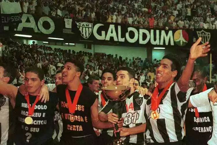 Falcão, considerado o melhor jogador de futsal, segura taça de campeão pelo Atlético-MG, em 1999, ao lado de Manoel Tobias e Índio