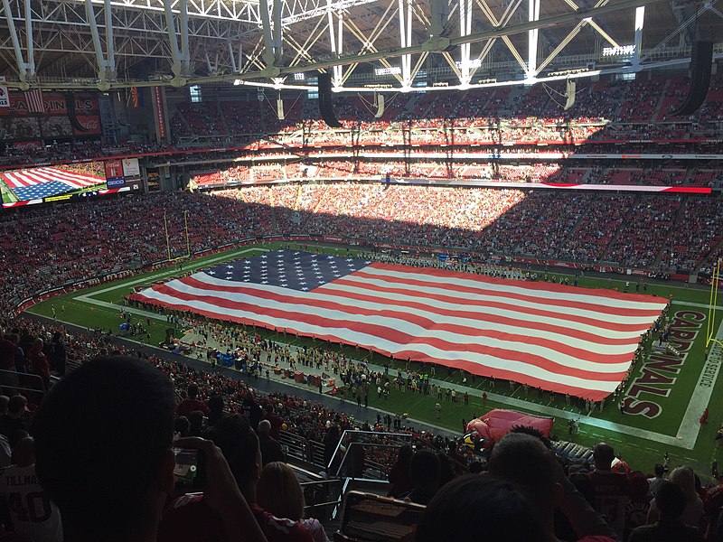 Estádio de futebol com uma bandeira dos EUA em campo.