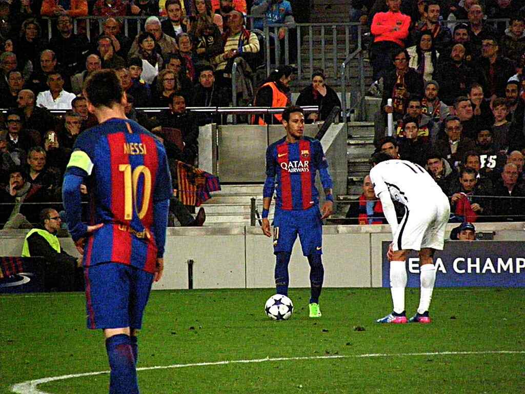 Neymar, em jogo pelo Barcelona contra o PSG, em posição para cobrança de falta, com um homem na berreira e Messi de costas.