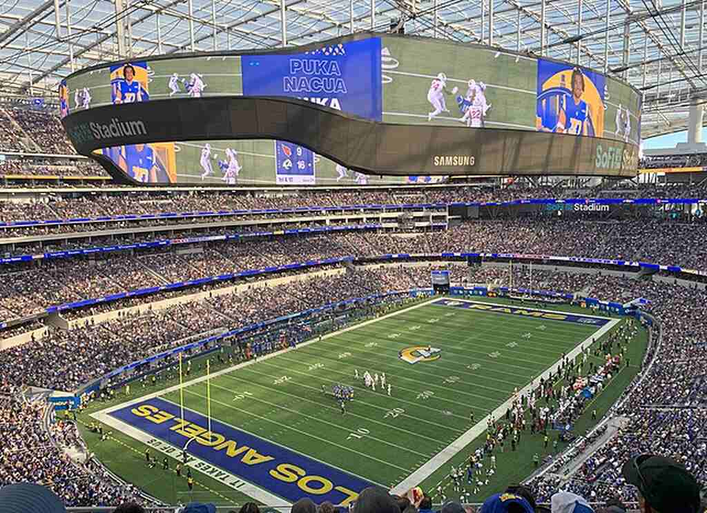 Estádio de futebol americano, visto do alto das arquibancadas, lotado, durante partida.