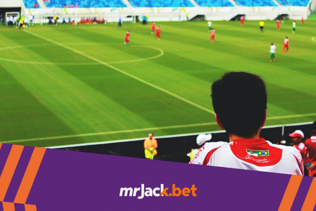 Jovem rapaz assistindo a partida de futebol na arquibancada do estádio.