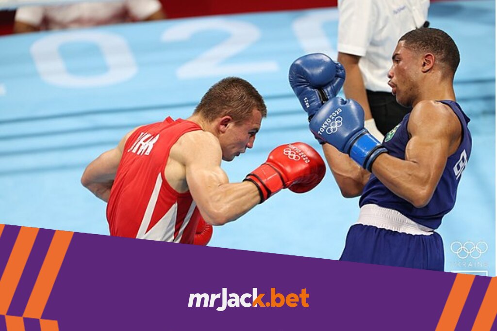 Lutador de boxe de vermelho golpeando o lutador vestido com uniforme azul, enquanto ele tenta se esquivar dos ataques.