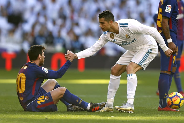 Cristiano Ronaldo ajudando Messi a levantar em uma partida de futebol - Foto: Getty Images