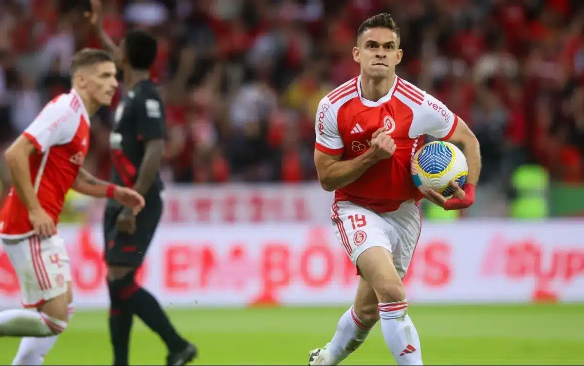 Jogador de futebol segurando uma bola e correndo