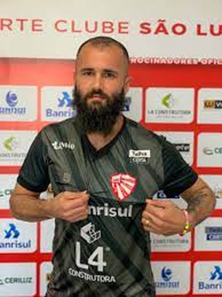 Jogador de futebol Fábio Rampi com uma barba extensa, puxando sua camisa para exibir o escudo do seu time.