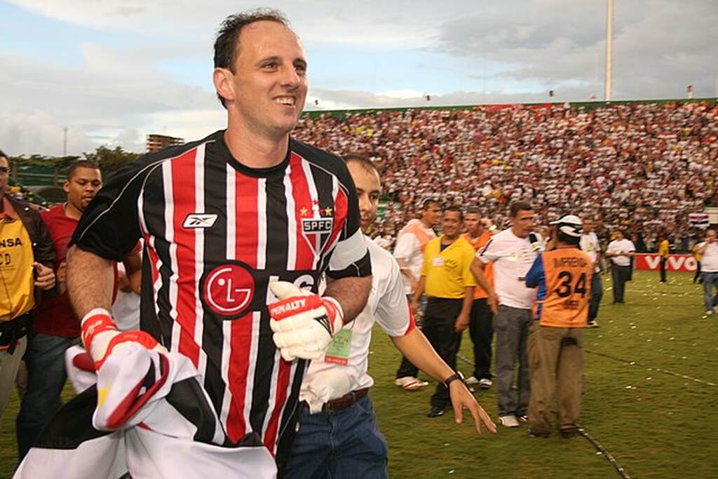 Ex-jogador de futebol, Rogério Ceni, correndo pelo campo em comemoração junto com a torcida.