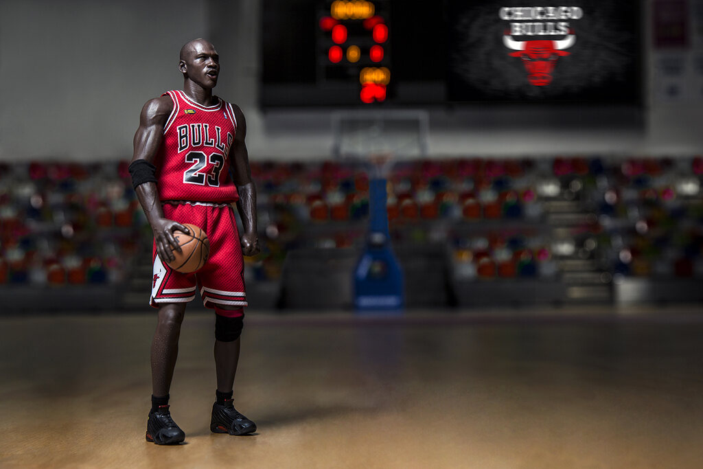 Ex-jogador de basquete Michael Jordan vestindo uniforme vermelho, no meio da quadra de basquete.