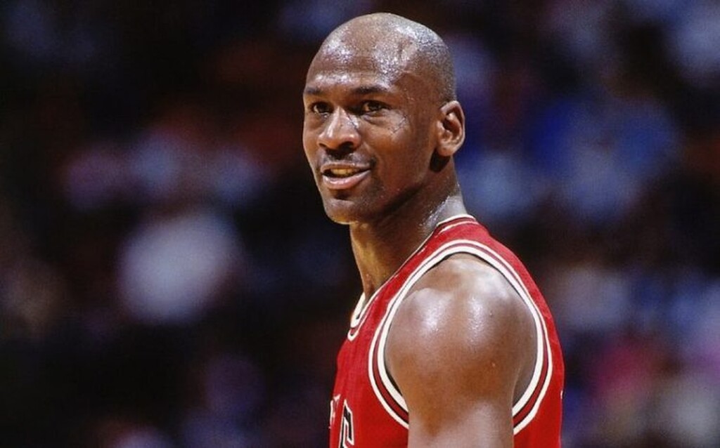 Jogador de basquete Michael Jordan, vestindo uniforme vermelho, soado, durante a partida.