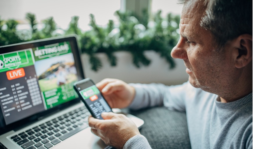 Pessoa apostando em um computador e um celular