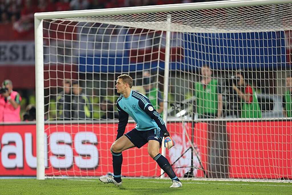 Goleiro do Bayern de Munique, Manuel Neuer posicionado no gol, pronto para realizar uma defesa durante a partida.