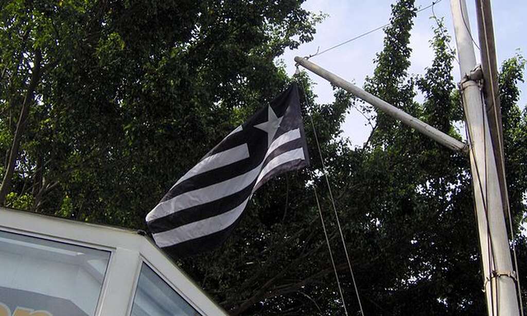 Bandeira preta e branca do Botafogo, colocada em mastro no meio da rua.