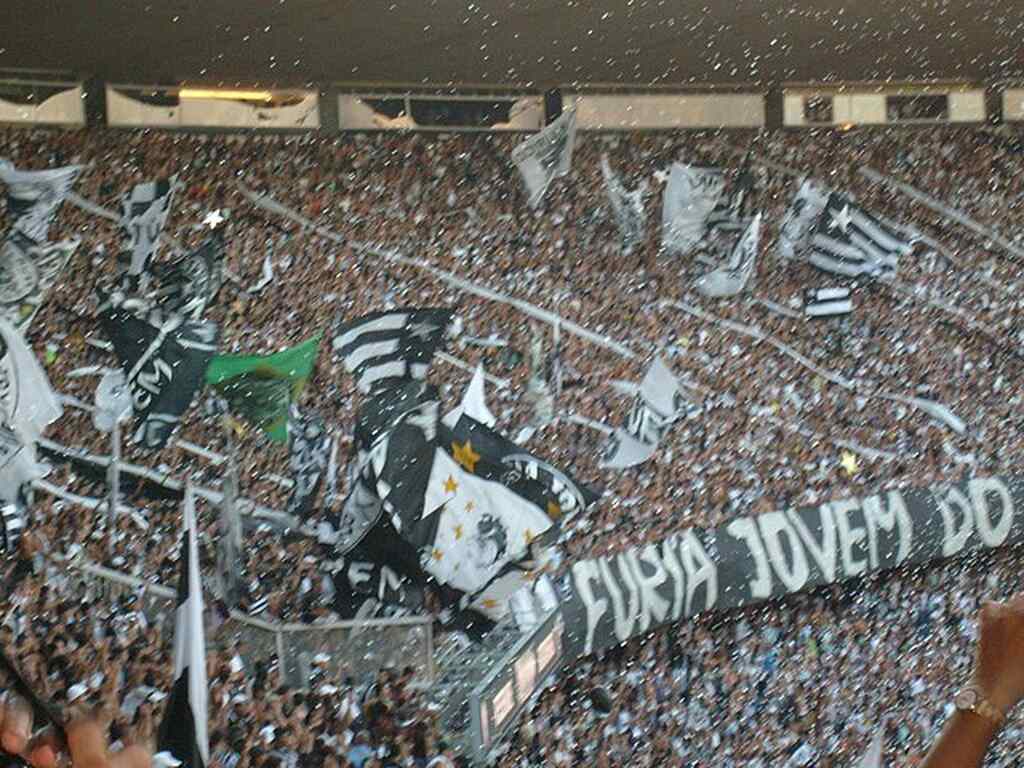 Torcida do Botafogo fazendo festa intensa nas arquibancadas do estádio, durante partida de futebol.