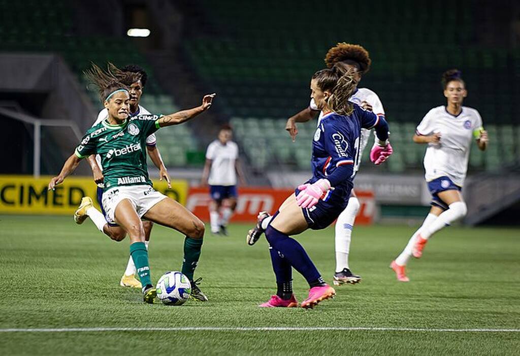 Jogadora do time feminino do Palmeiras disputando uma bola com a goleira do time adversário.