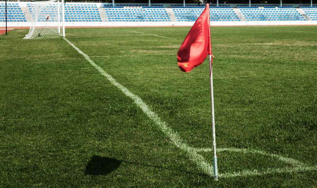 um escanteio limite com uma bandeira vermelha no campo de gramado verde