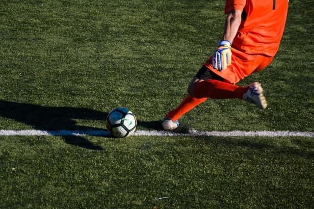 Jogador contratado na janela de transferência chutando bola de futebol no campo