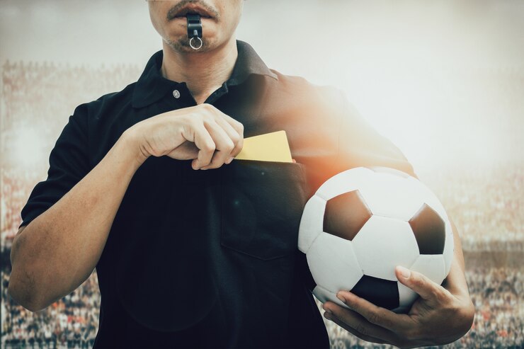 Juiz tirando o cartão do bolso da camisa e com um apito - Foto Freepik