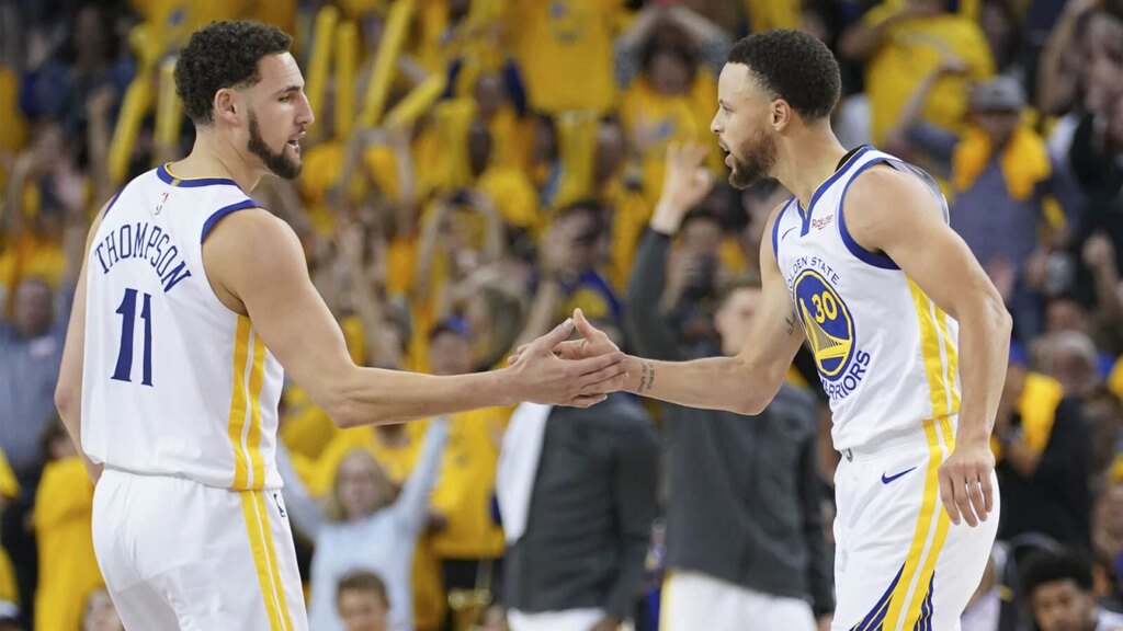 Jogadores Klay Thompsom e Stephen Curry se cumprimentando em partida do Golden State Warrior na NBA