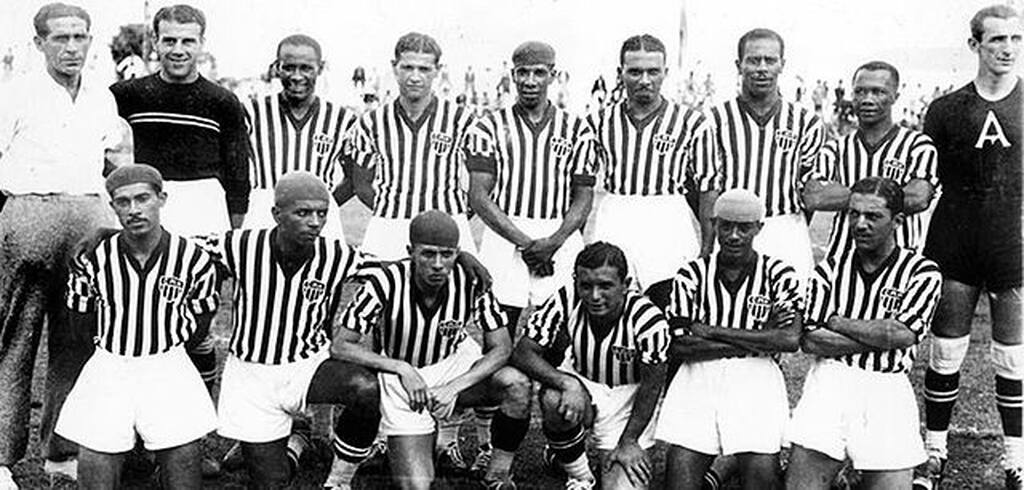 Elenco do Atlético-MG, com camisa listrada e calção branco enfileirados para foto antes do início da partida.