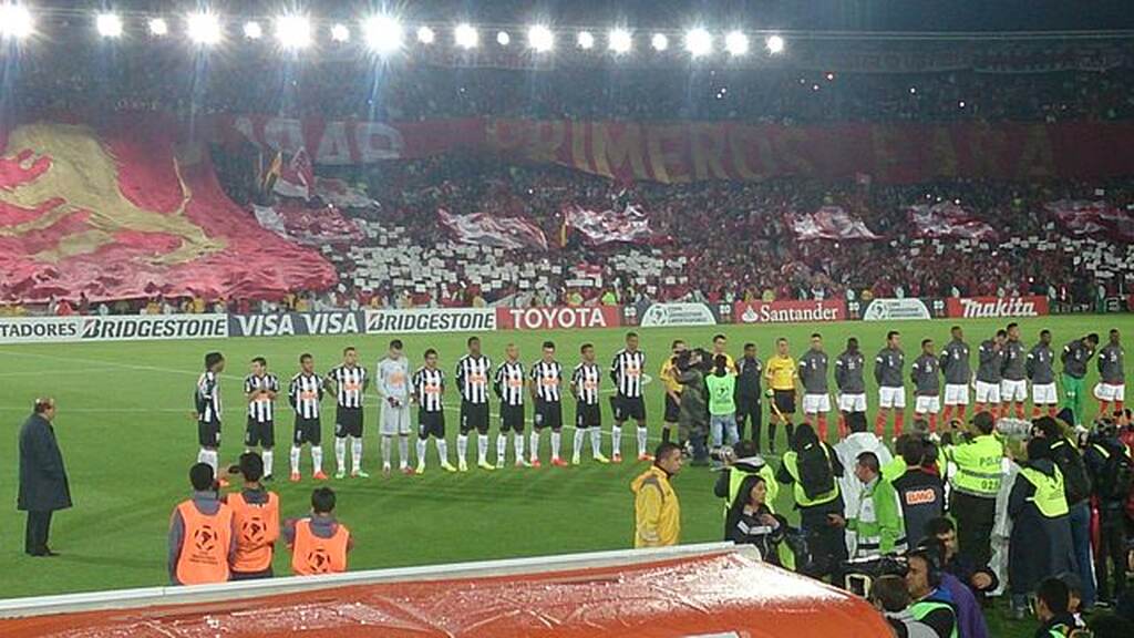 Jogadores do Atlético-MG em campo, durante execução do hino, preparados para o jogo.