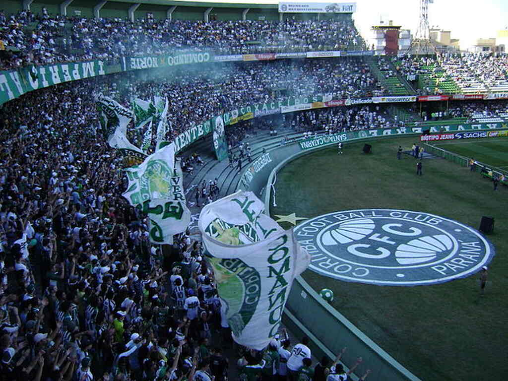 Torcida do Coritiba fazendo festa nas arquibancadas do estádio durante partida de futebol.