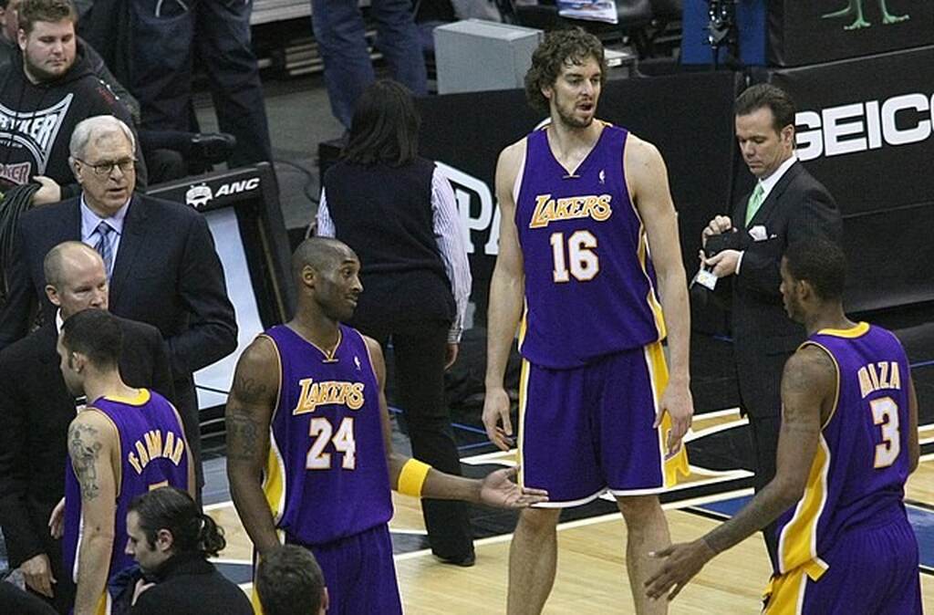 Jogadores do Los Angeles Lakers de uniforme roxo, conversam entre si, em intervalo durante uma partida.