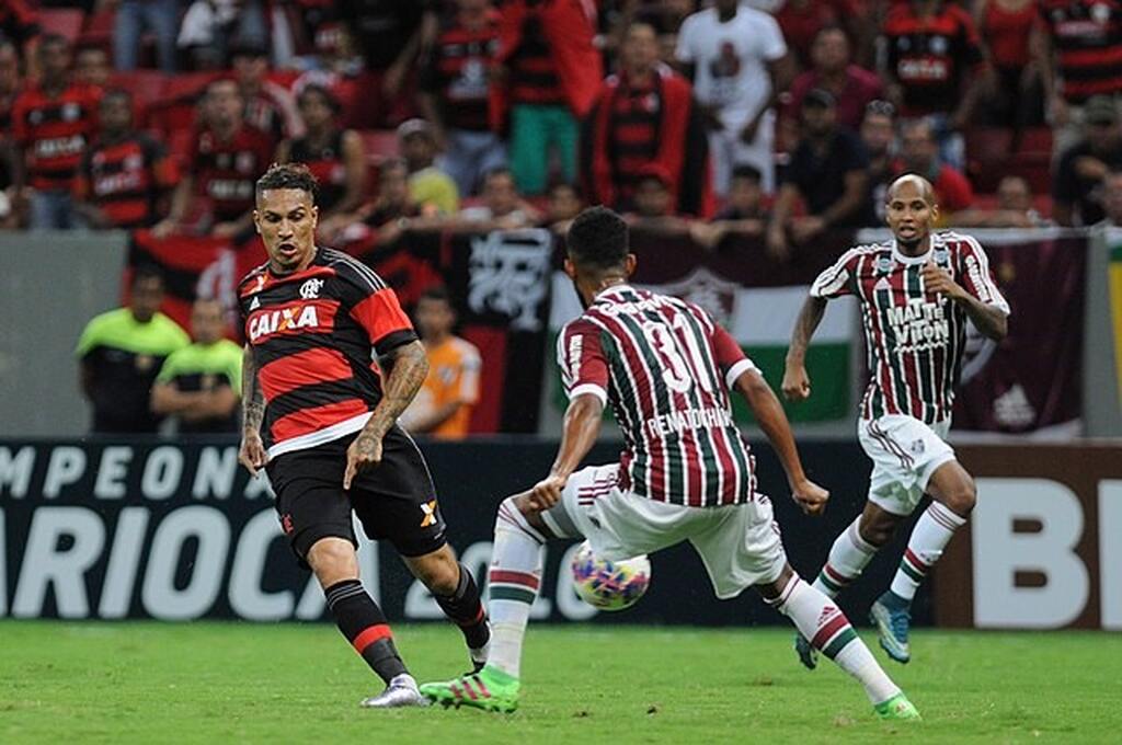 Paolo Guerrero, na época jogador do Flamengo, tentando passar a bola diante de um jogador do Fluminense.