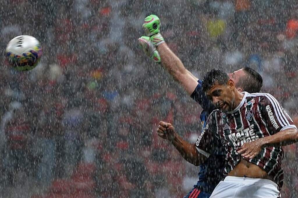 Diego Souza, na época jogador do Fluminense disputa bola pelo alto com o goleiro do time adversário durante partida.