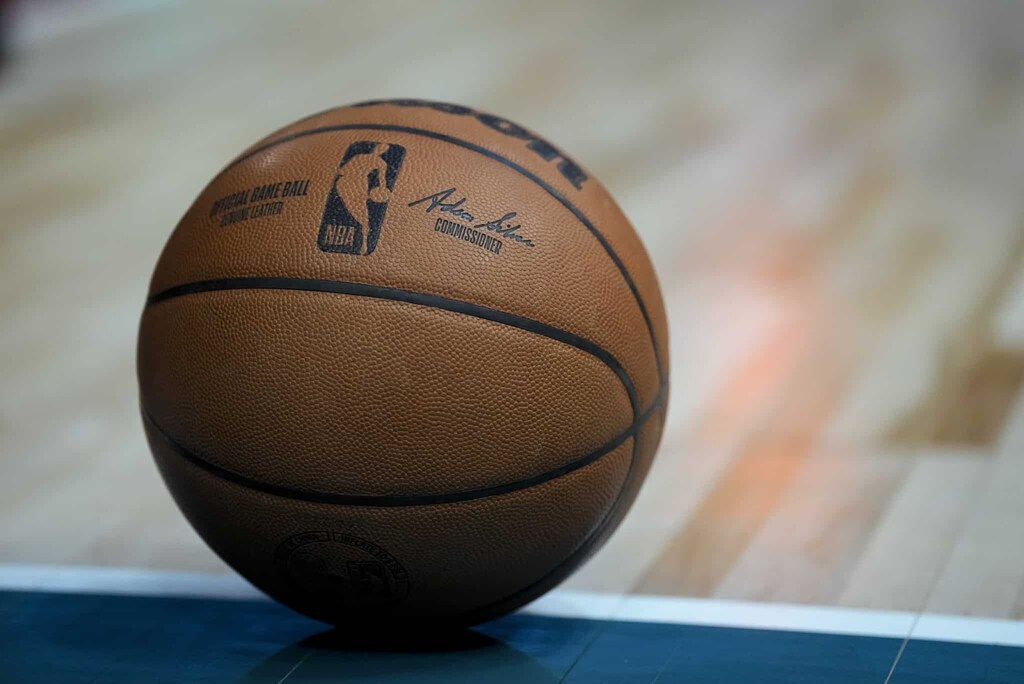 Bola de basquete com o logo da NBA no piso de uma quadra.