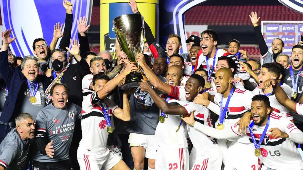 Jogadores e membros da comissão técnica do São Paulo comemorando, enquanto levantam a taça do campeonato paulista.