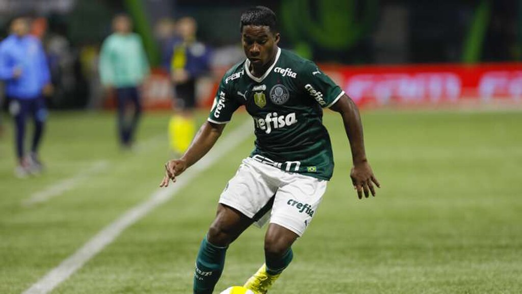 Endrick, jogador do Palmeiras, usando o uniforme tradicional de camisa verde e calção branco, conduz a bola durante partida.