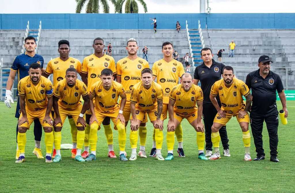 Elenco do Amazonas Futebol Clube enfileirado no gramado junto de comissão técnica antes da partida.