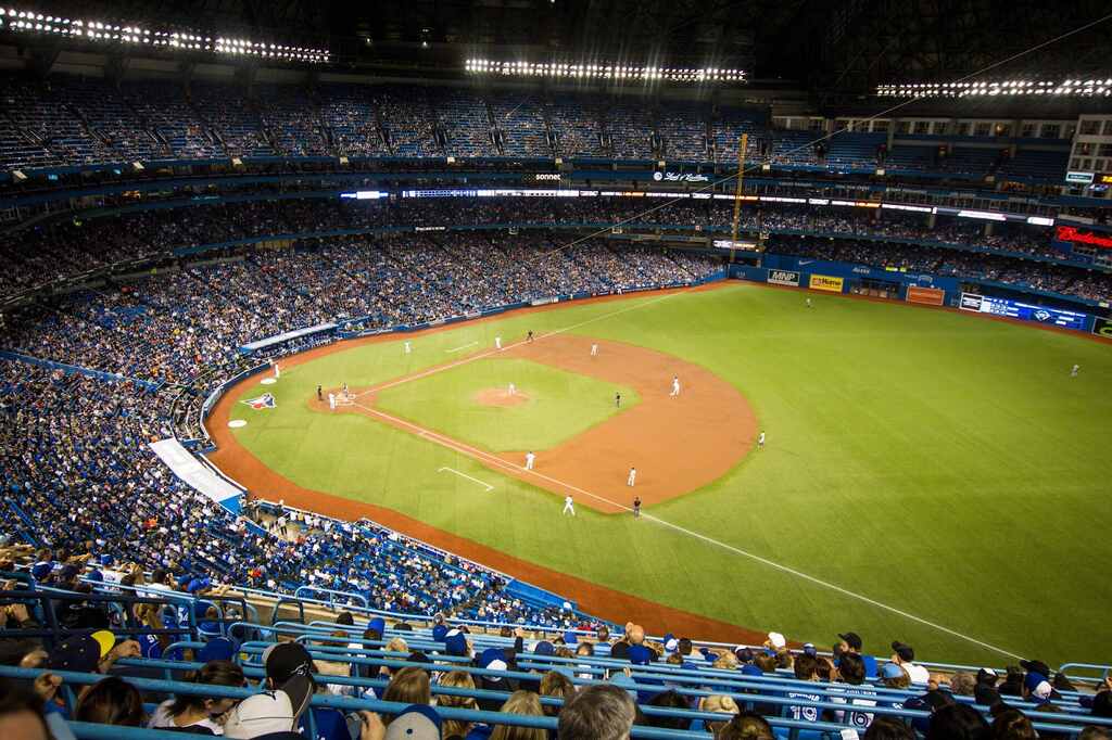 Estádio de baseball lotado, com jogadores em campo durante partida.