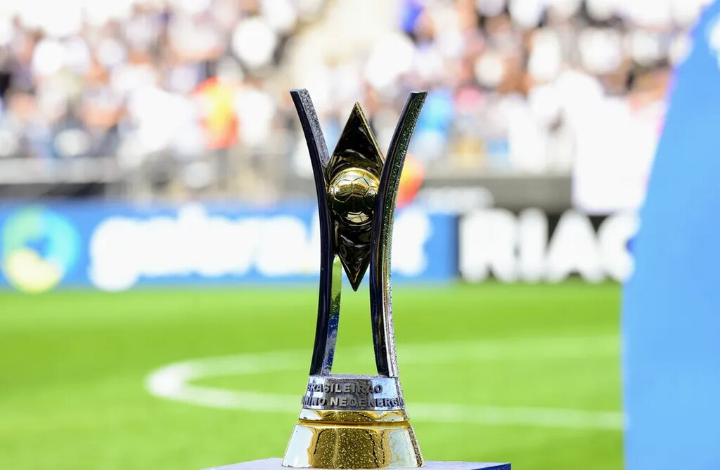 Taça do Brasileirão feminino coloca em suporte no meio do gramado em um estádio lotado, com arquibancadas cheias.