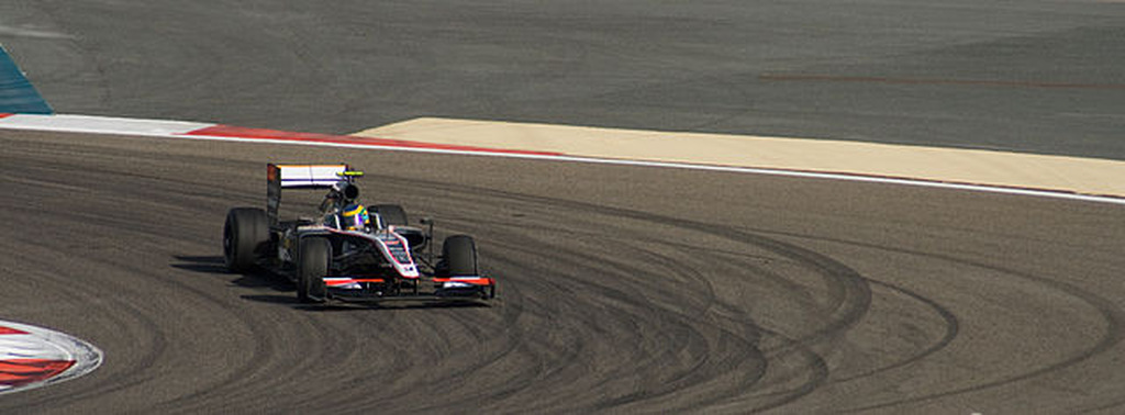 Carro de corrida fazendo curva em pista de Fórmula 1 durante competição.