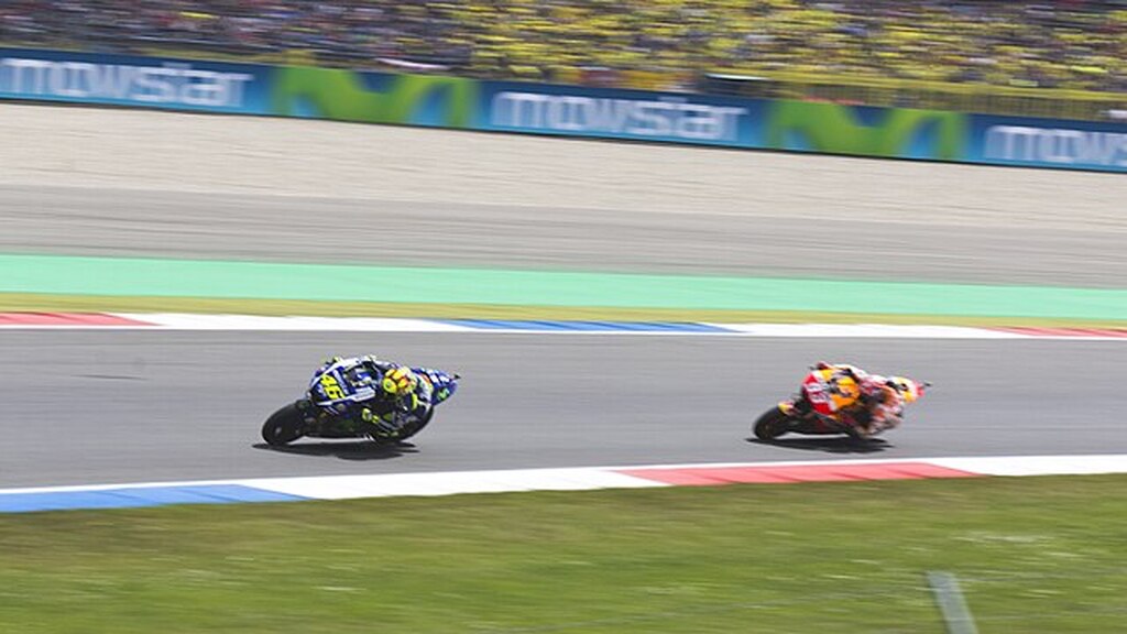 Duas pilotos de moto fazendo uma curva em alta velocidade em uma corrida profissional.