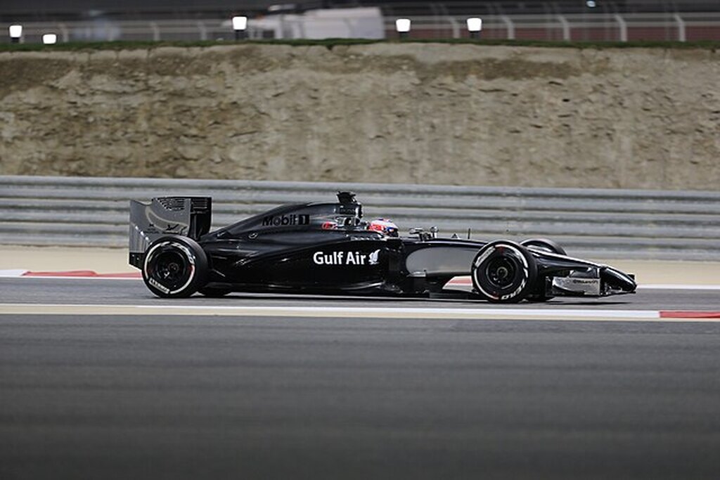 Carro inteiramente preto acelerando em pista de corrida da Fórmula 1 durante competição.