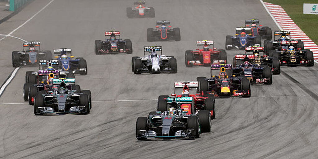 Diversos carros de corrida, com cores diferentes, espalhados por uma pista cinza de fórmula 1.