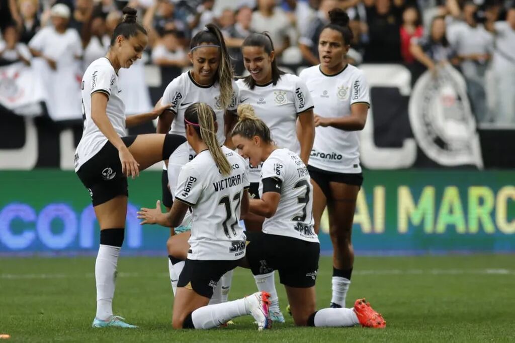 Jogadoras do time feminino de futebol do Corinthians comemorando um gol marcado durante a partida.