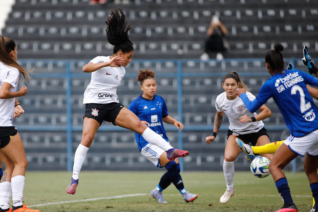 Jogadora do time feminino do Corinthians cabeceando uma bola no meio da área, cercada por jogadoras do Cruzeiro.