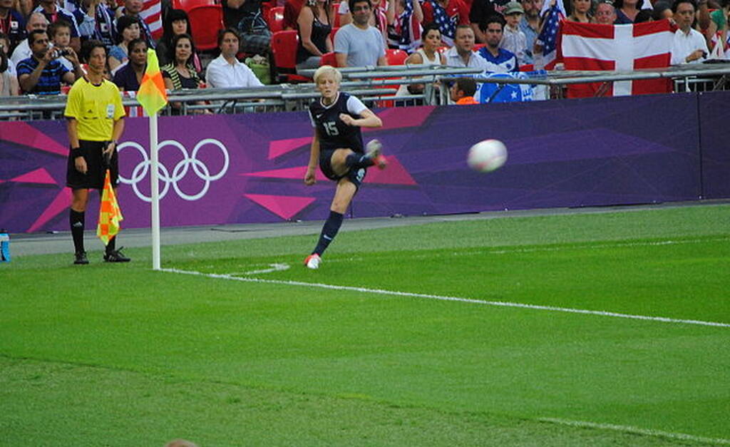 Jogadora de futebol feminino realizando cobrança de escanteio durante partida entre seleções.