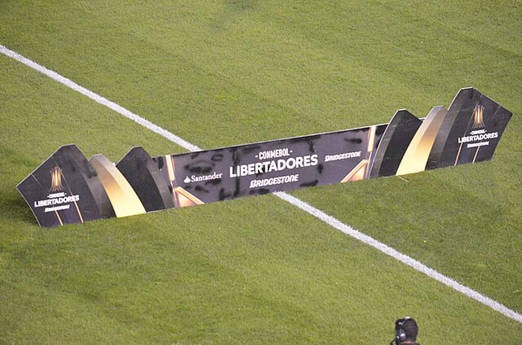 Placa da competição Libertadores mostrando os patrocinadores do torneio no meio do gramado.