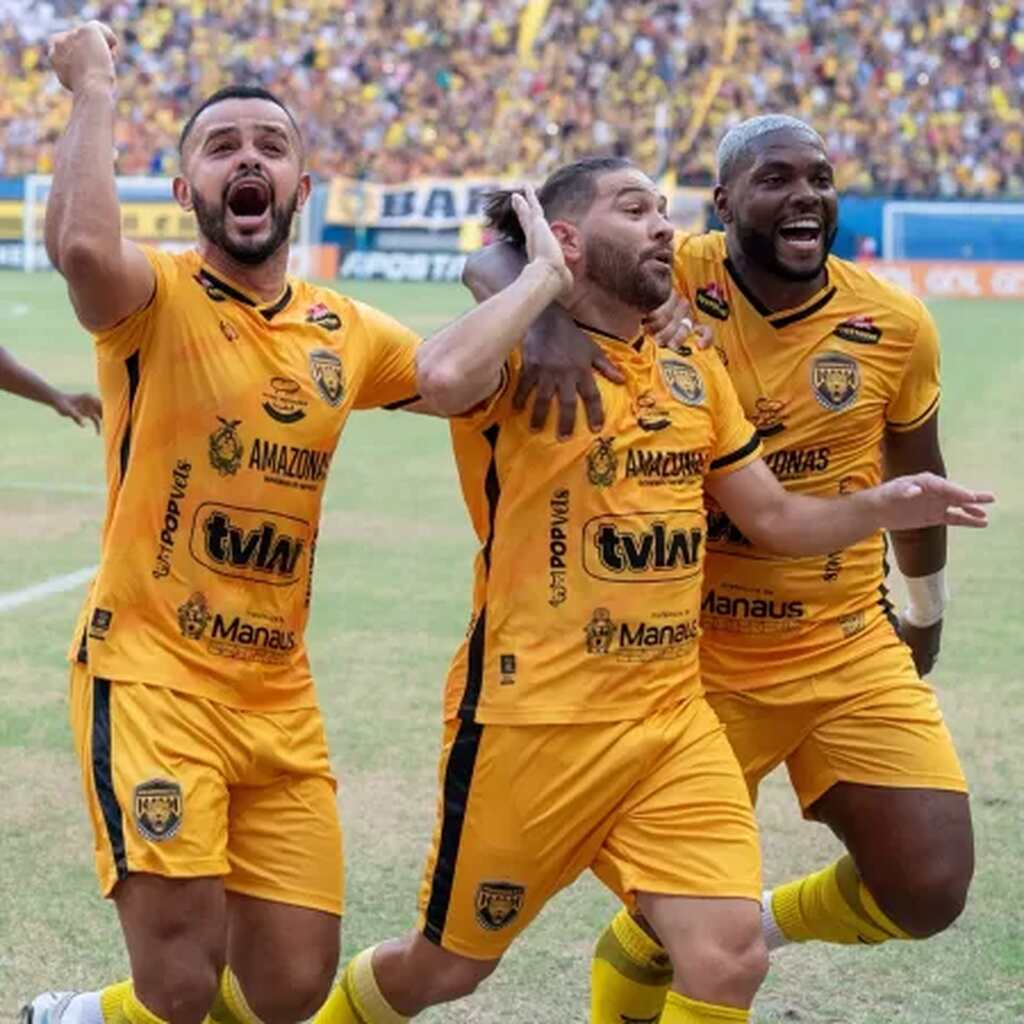 Jogadores do Amazonas FC, vestindo uniforme amarelo com detalhes pretos correndo pelo gramado comemorando um gol.