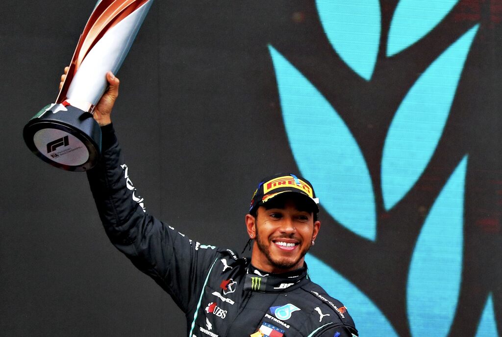 Piloto de formula 1 Lewis Hamilton levantando a taça após uma vitória