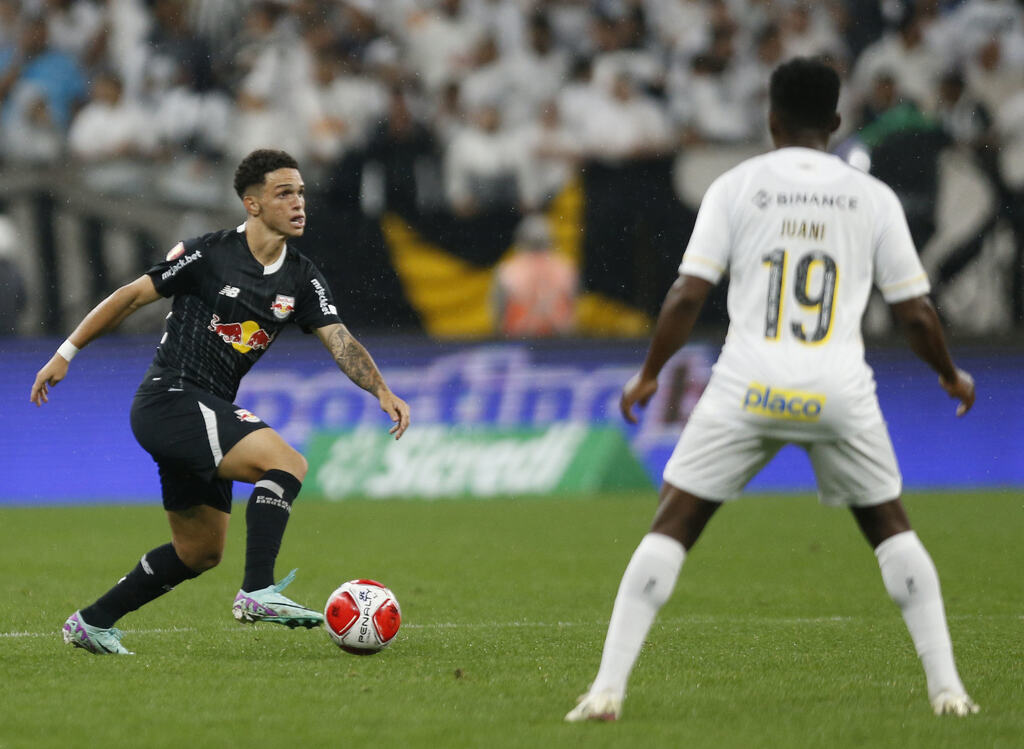 Jogador do Red Bull Bragantino, vestindo uniforme preto, conduzindo a bola enquanto é marcado por jogador do Santos.