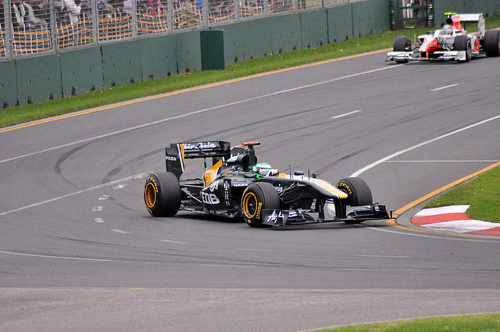 Carro de corrida, realizando curva em do circuito de Fórmula 1 durante disputa.