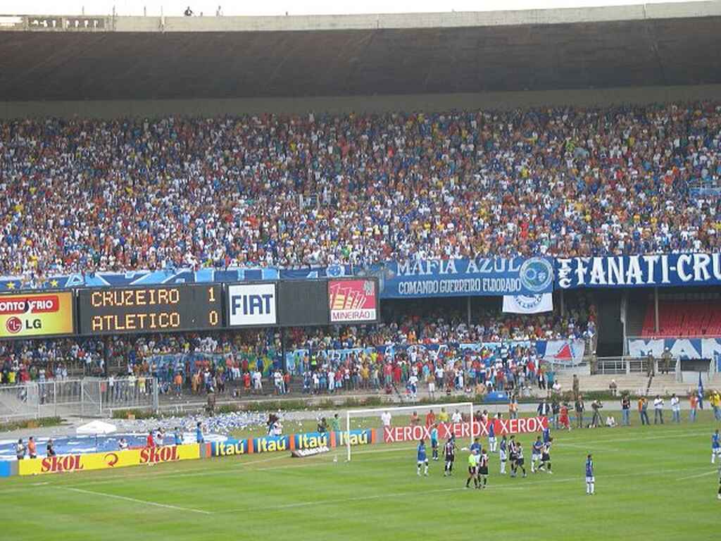 Jogadores do Cruzeiro e do Atlético concentrados dentro da grande área, durante partida com arquibancadas lotadas.