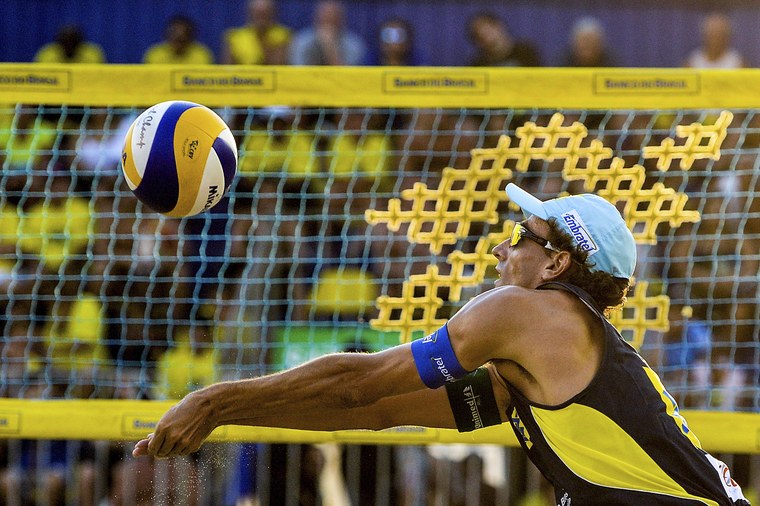 Jogador de volei de praia recebendo uma bola na rede