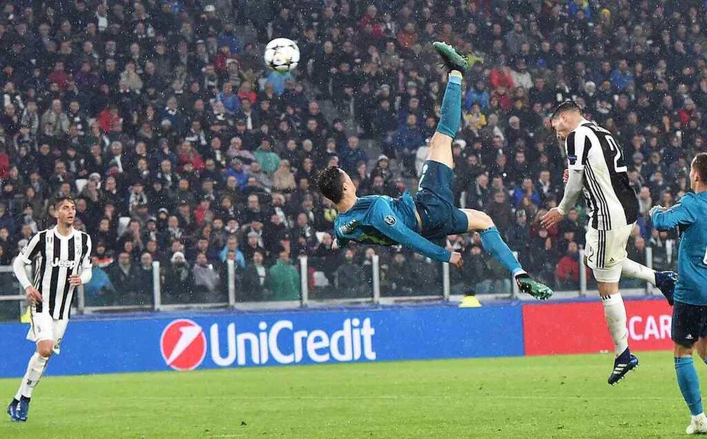 Jogador de futebol, Cristiano Ronaldo, vestindo uniforme azul, acertando gol de bicicleta contra a Juventus.