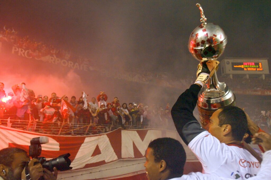 Elenco do Internacional de 2006 comemorando título da Libertadores junto da torcida no estádio.