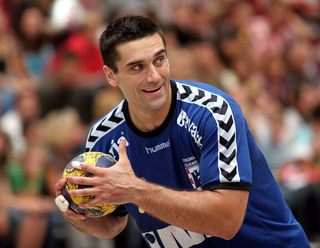 Jogador de handebol Kiril Lazarov, vestindo uniforme azul, enquanto segura bola de handebol durante partida.